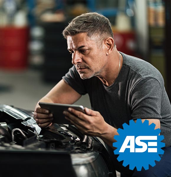 Car mechanic using digital tablet while repairing analyzing engine in auto repair shop.